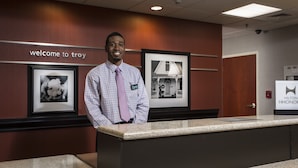 A reception desk with a "welcome to troy" sign, framed pictures on the wall, and a Hilton Honors sign. - Hampton Inn by Hilton Troy (Troy)