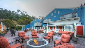 A patio area with outdoor seating and a central fire pit. - The Rigdon House (Cambria)