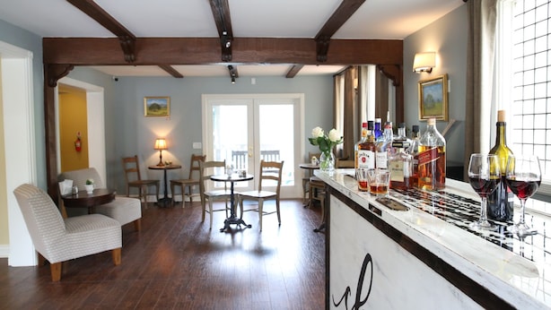 A dining area with wooden chairs, a table, and a bar with bottles and glasses. - The Rigdon House (Cambria)