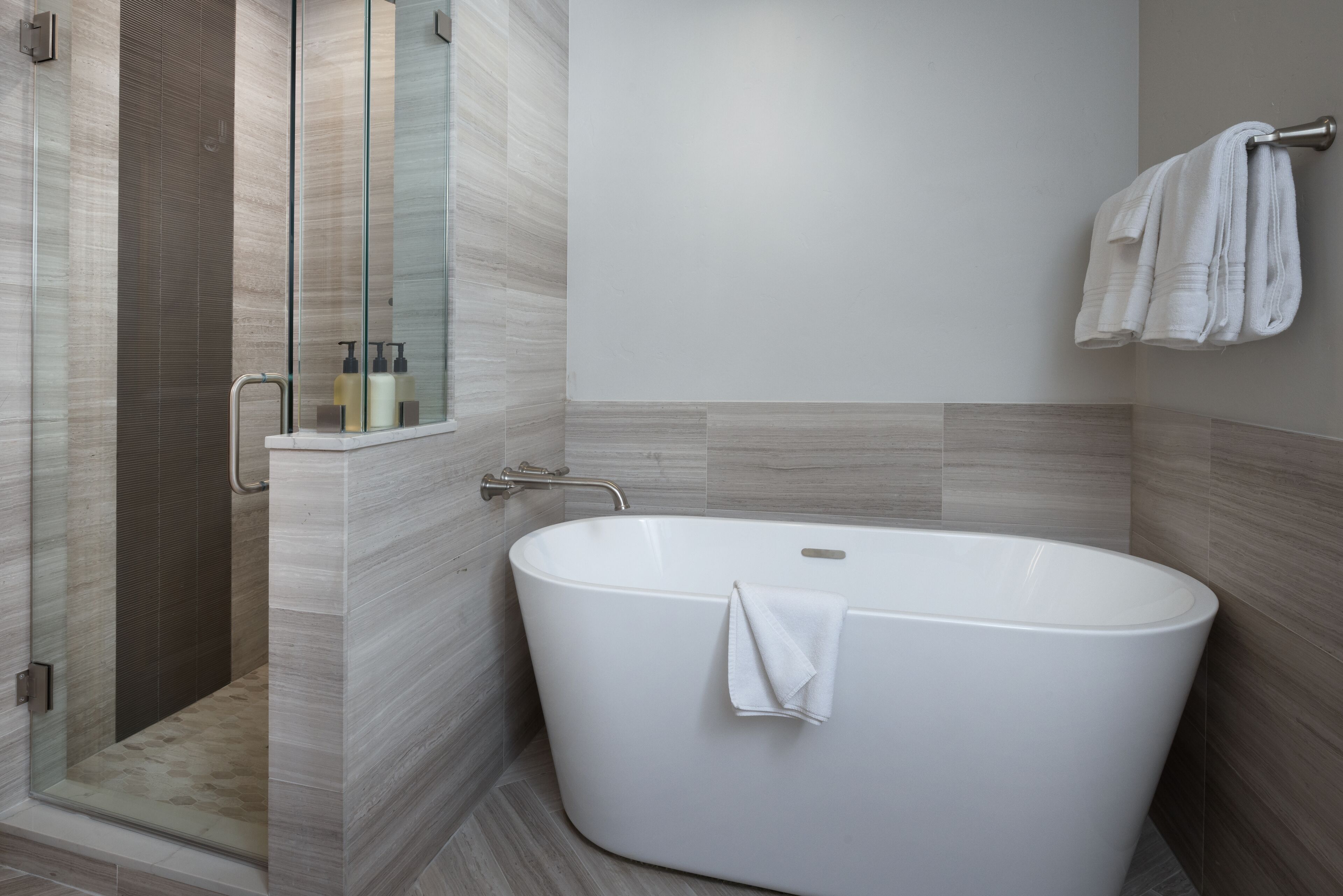 A modern bathroom with a freestanding bathtub, a glass shower enclosure, and a towel rack.
