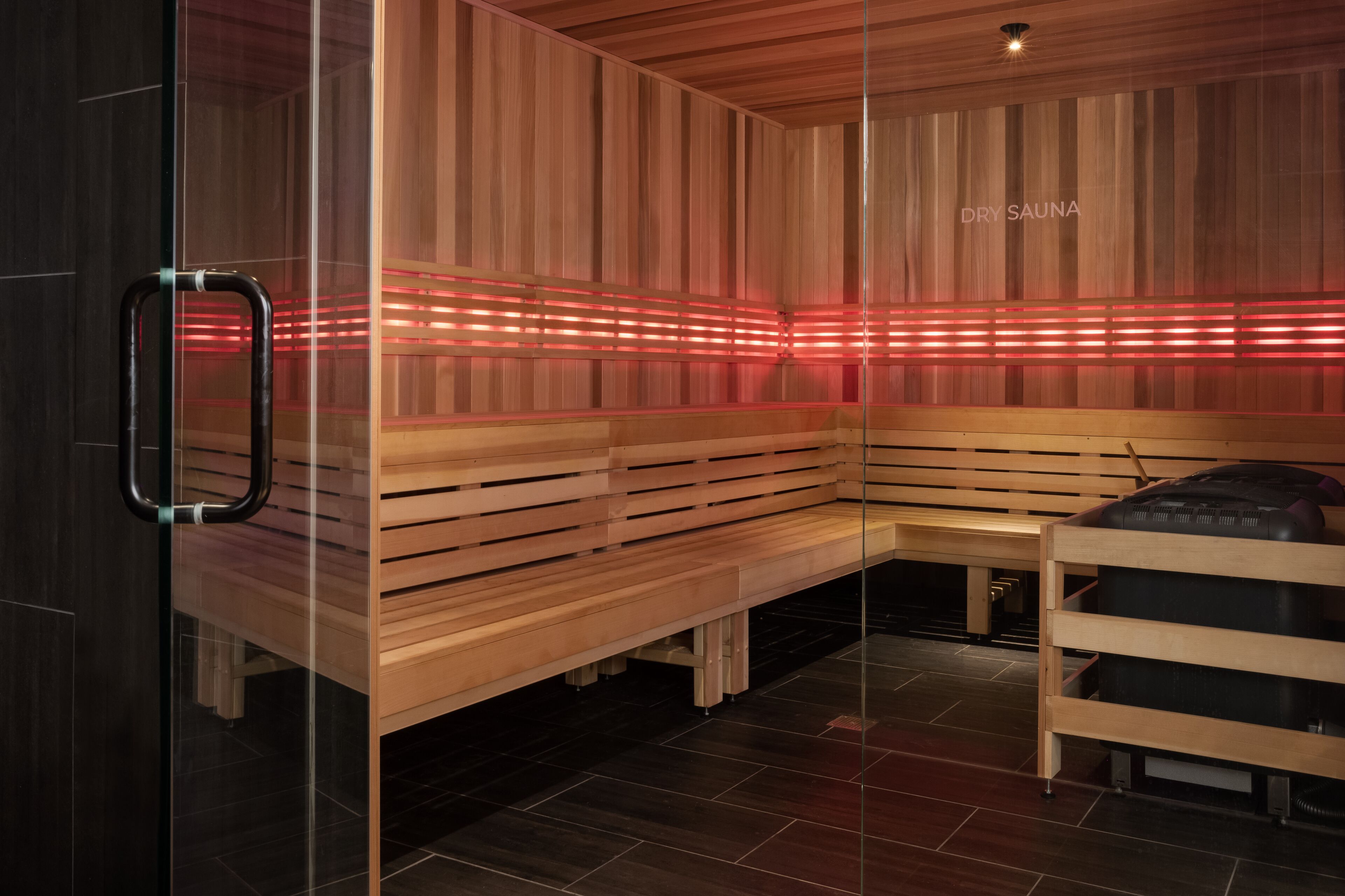 A dry sauna with wooden benches and red LED lighting.