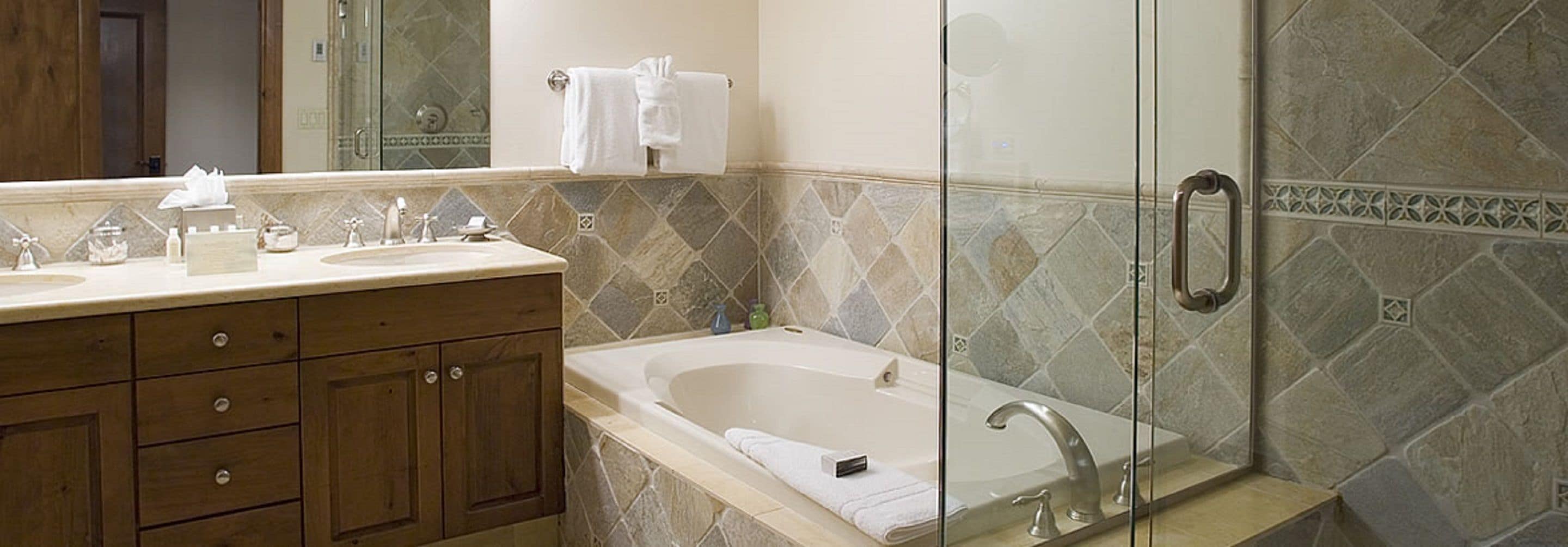 A bathroom with a double sink vanity, a bathtub, and a glass shower enclosure.