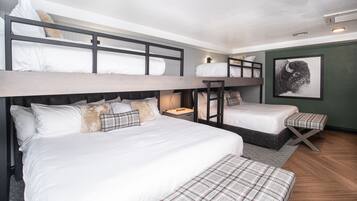 A bunk bed room with a wooden headboard, a bedside table with a lamp, and a framed picture on the wall.