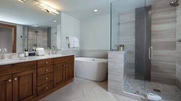 A modern bathroom with a glass-enclosed shower, a freestanding bathtub, and a double vanity with wooden cabinets.