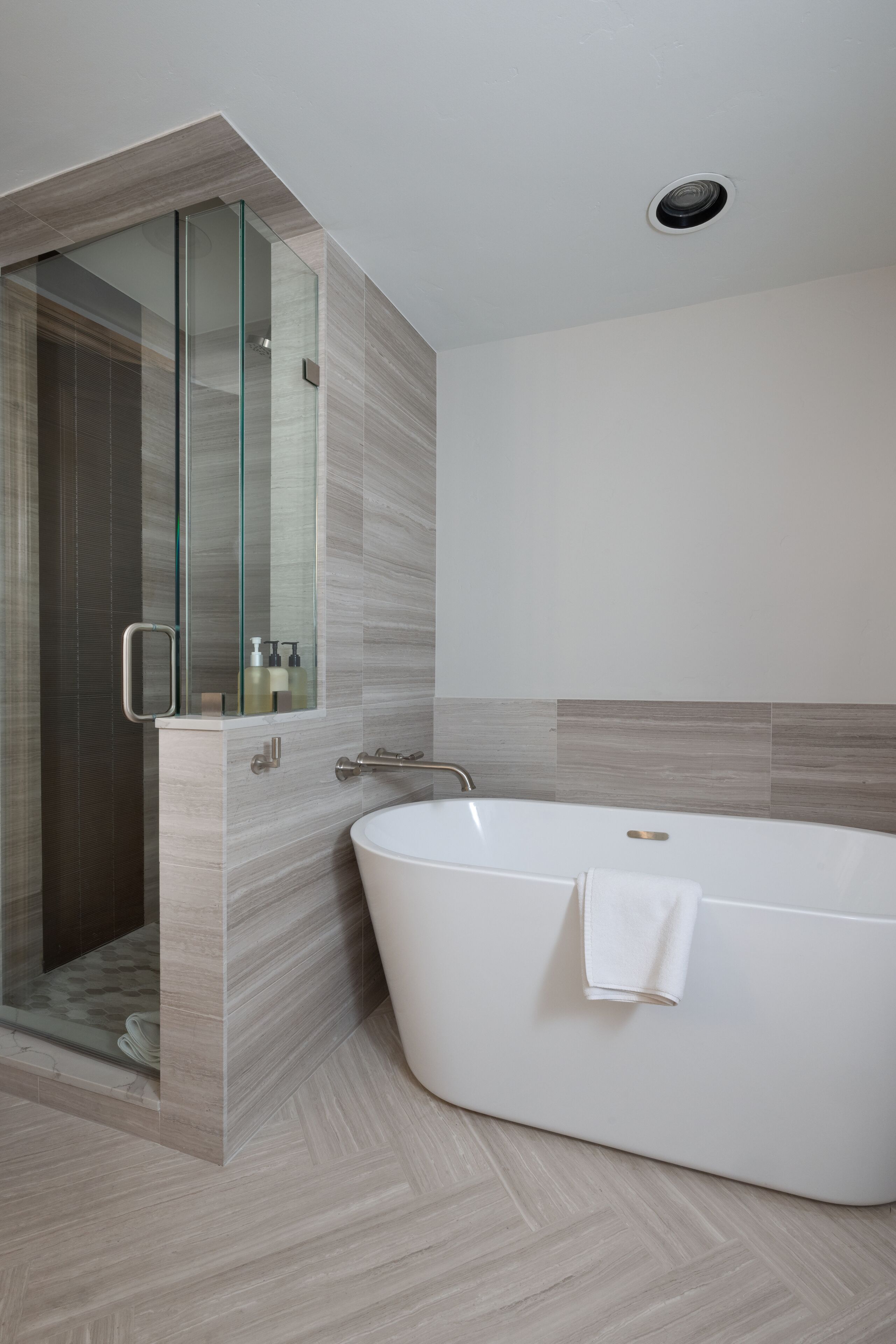 A modern bathroom with a freestanding bathtub, a glass-enclosed shower, and a minimalist design.