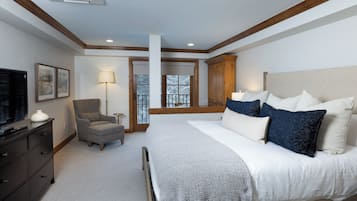 A bedroom with a large bed, a chair, a dresser, and a television.