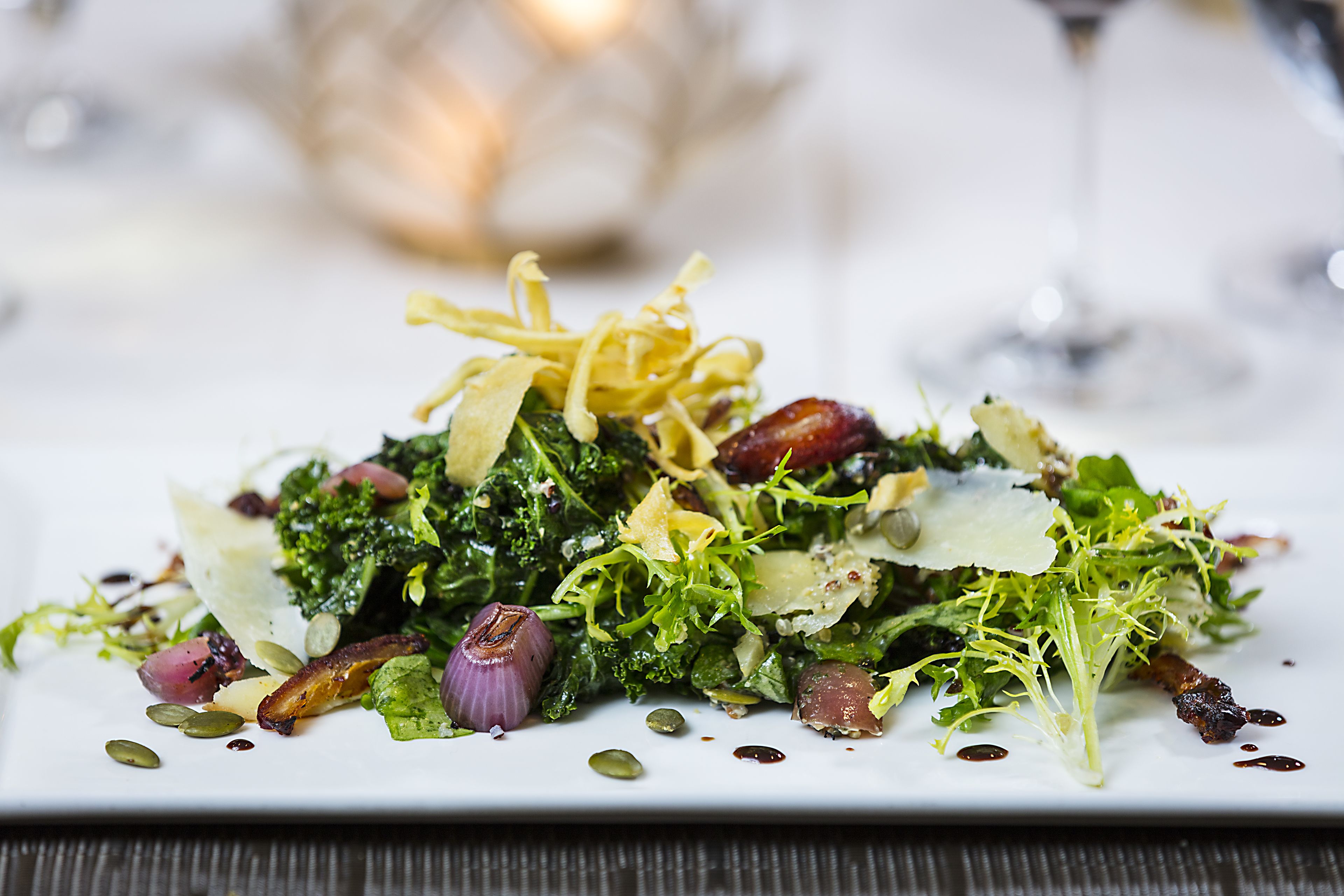A plated dish with greens, nuts, and cheese.