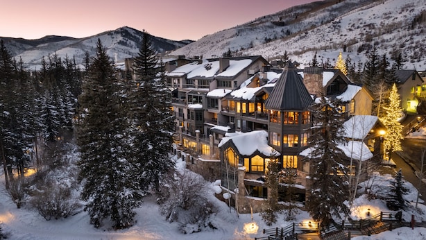 Un hôtel à plusieurs étages, avec des toits enneigés et une chaîne de montagnes en arrière-plan.