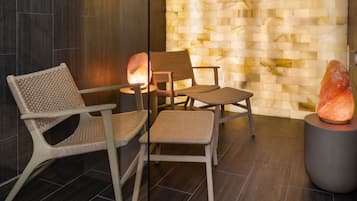 Un salón de sal con tres sillones de mimbre, una piedra caliente y una pared con textura.