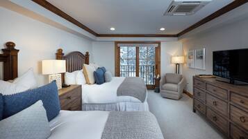 A hotel room with two beds, a TV, a desk with a lamp, a chair, and a large window.