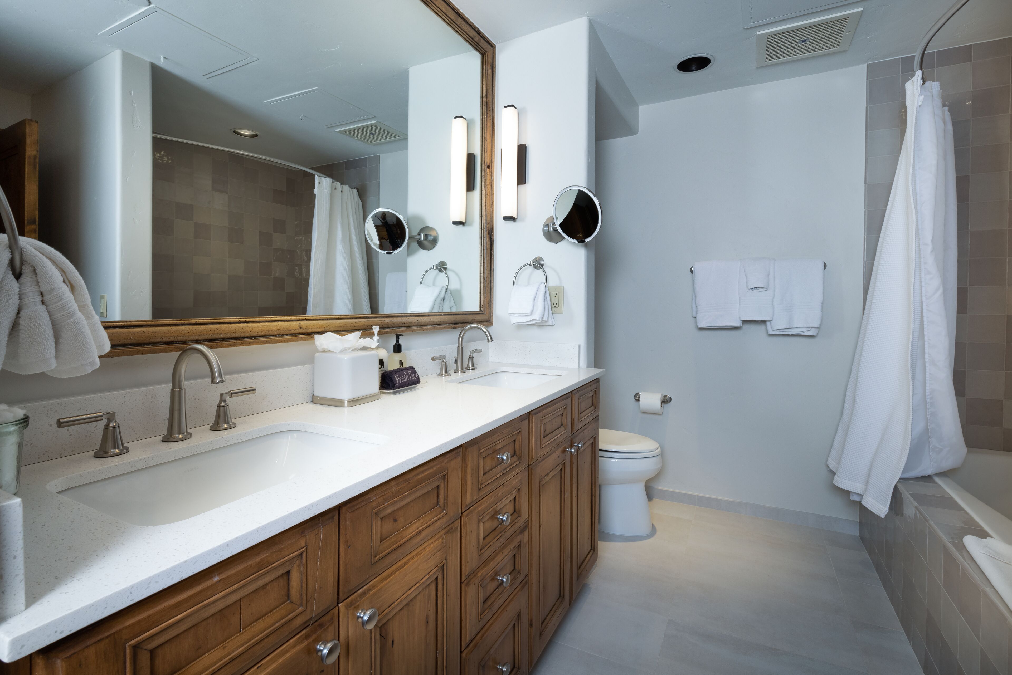 Une salle de bain moderne avec un grand miroir, un meuble-lavabo en bois, un lavabo blanc et une baignoire.