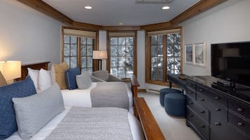 A bedroom with two beds, a dresser, and a television.