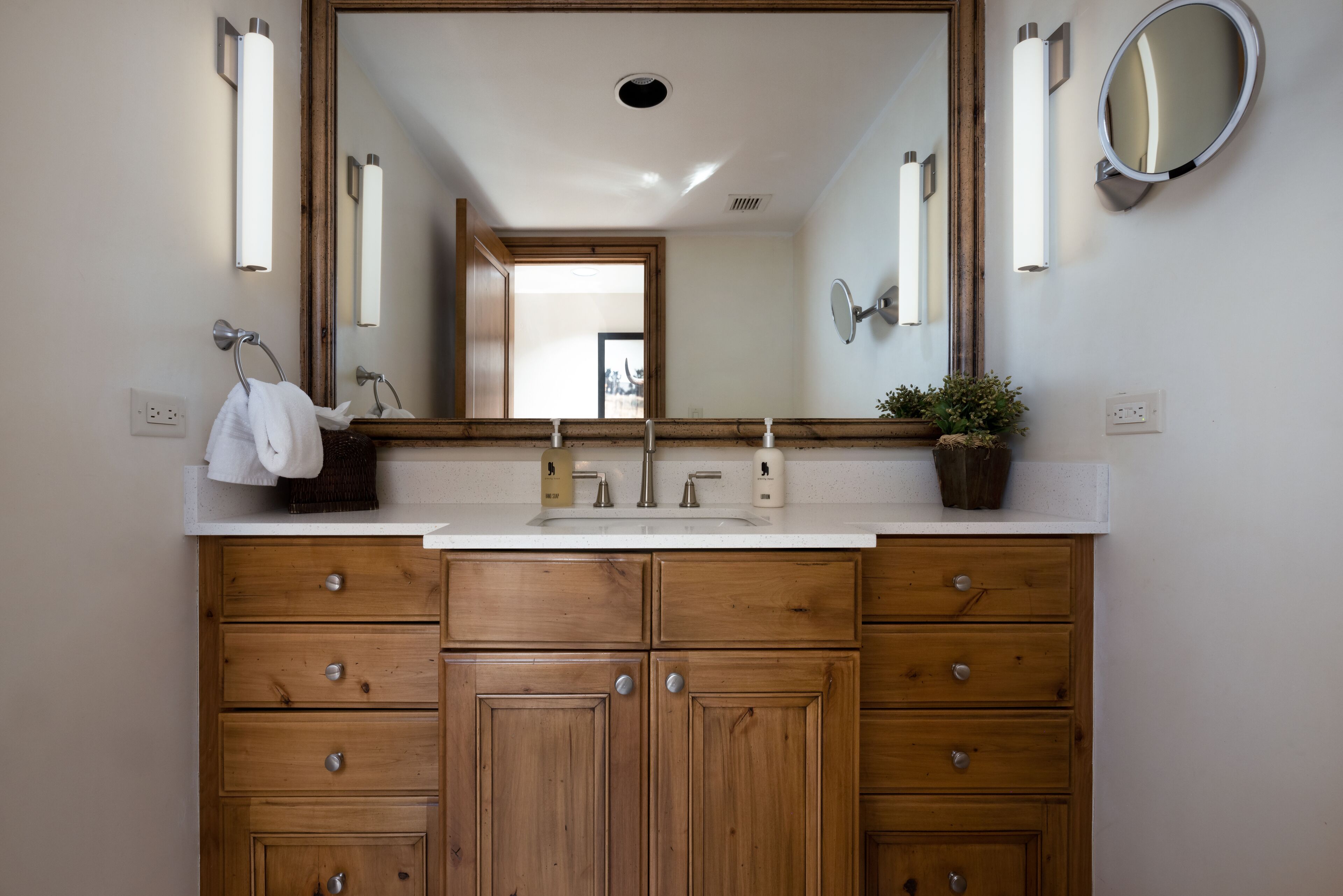 A bathroom with a wooden vanity, a large mirror, and a white sink.
