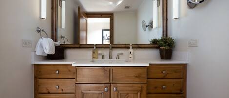 A bathroom with a wooden vanity, a large mirror, and a white sink.