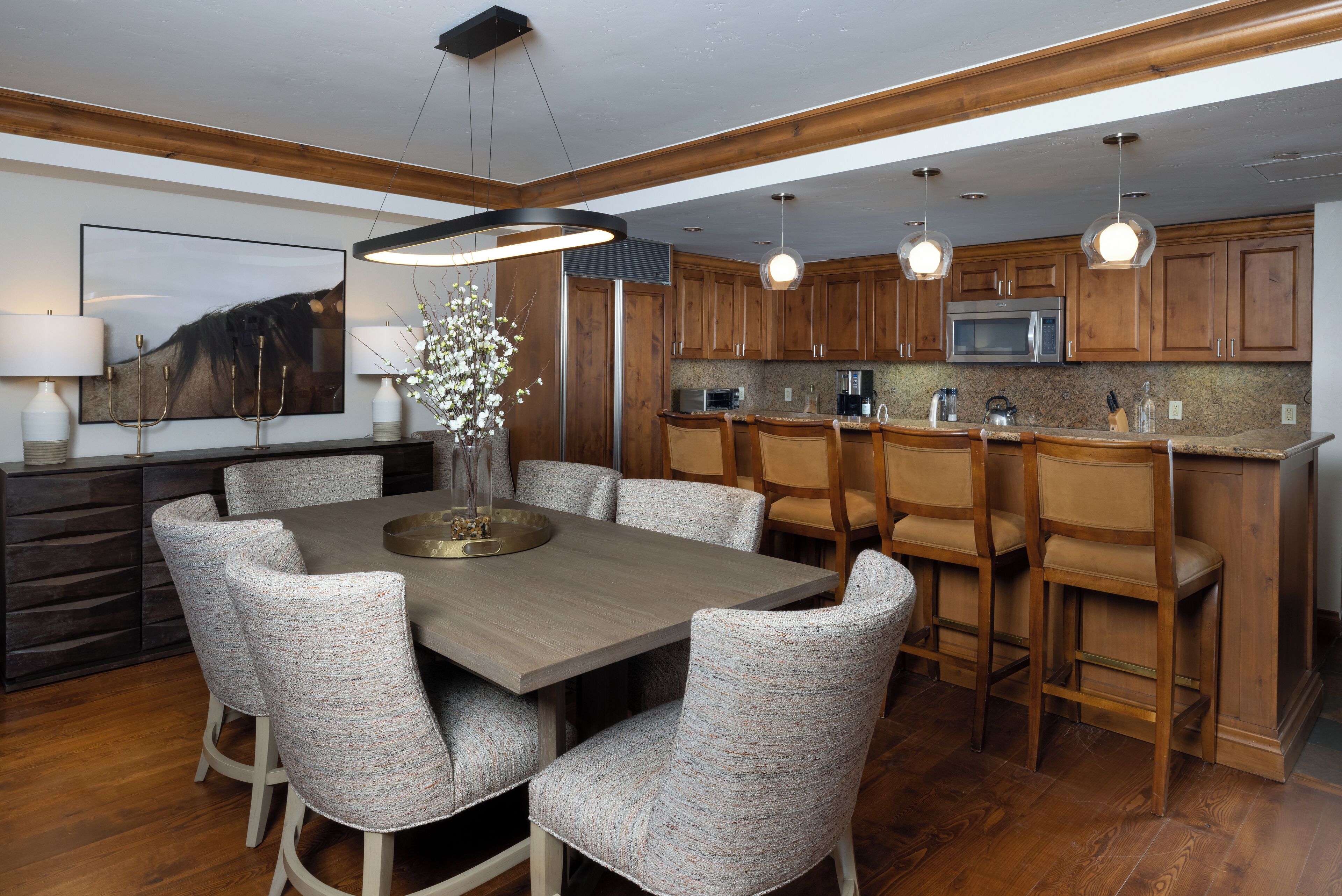 A modern kitchen with wooden cabinets, a central island with seating, and pendant lighting.