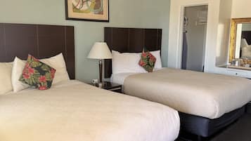 A hotel room with two beds, a ceiling fan, a framed artwork, a nightstand, and a mirror.