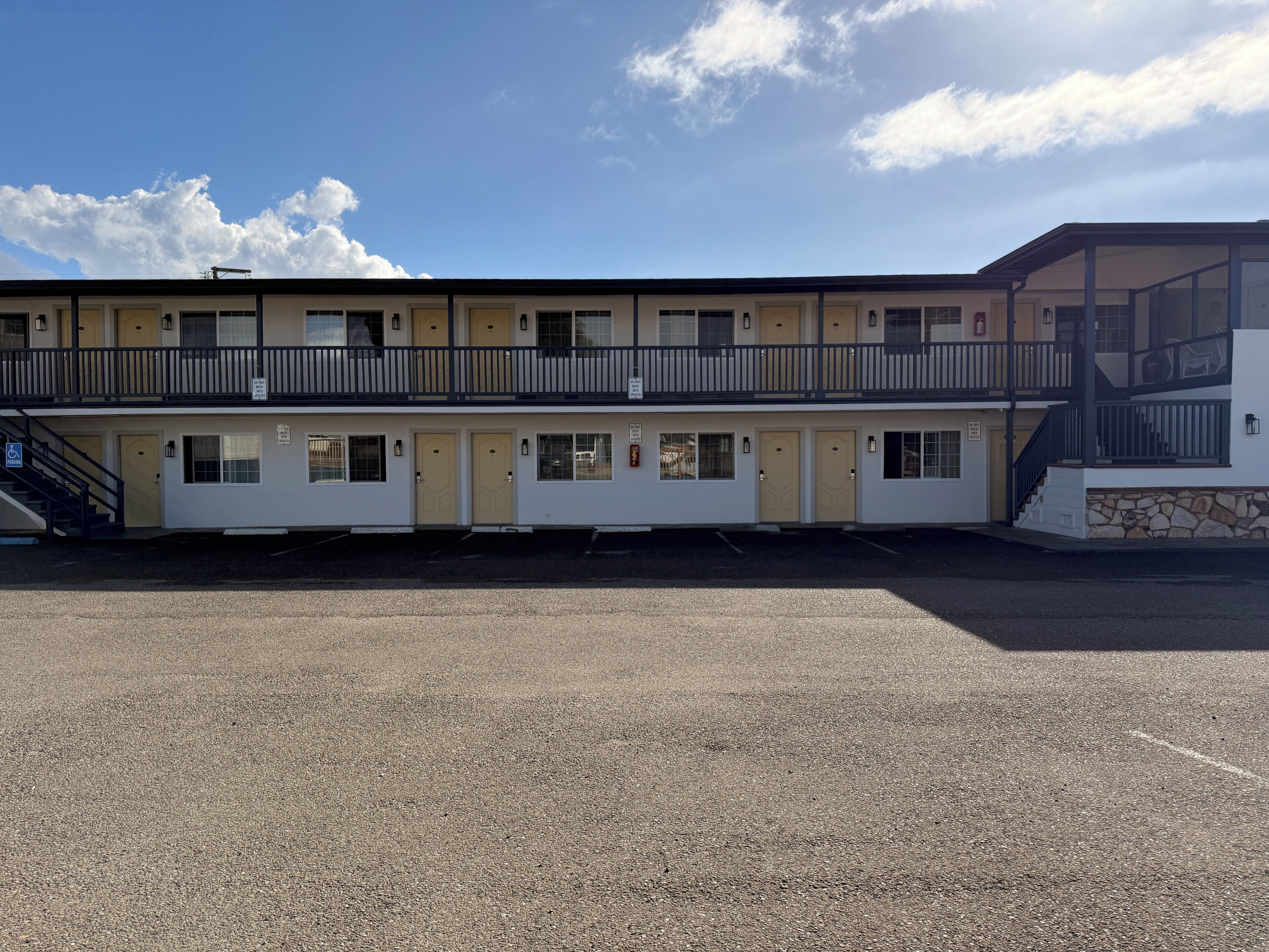 A motel with a two-story structure, a covered outdoor area, and a parking lot.