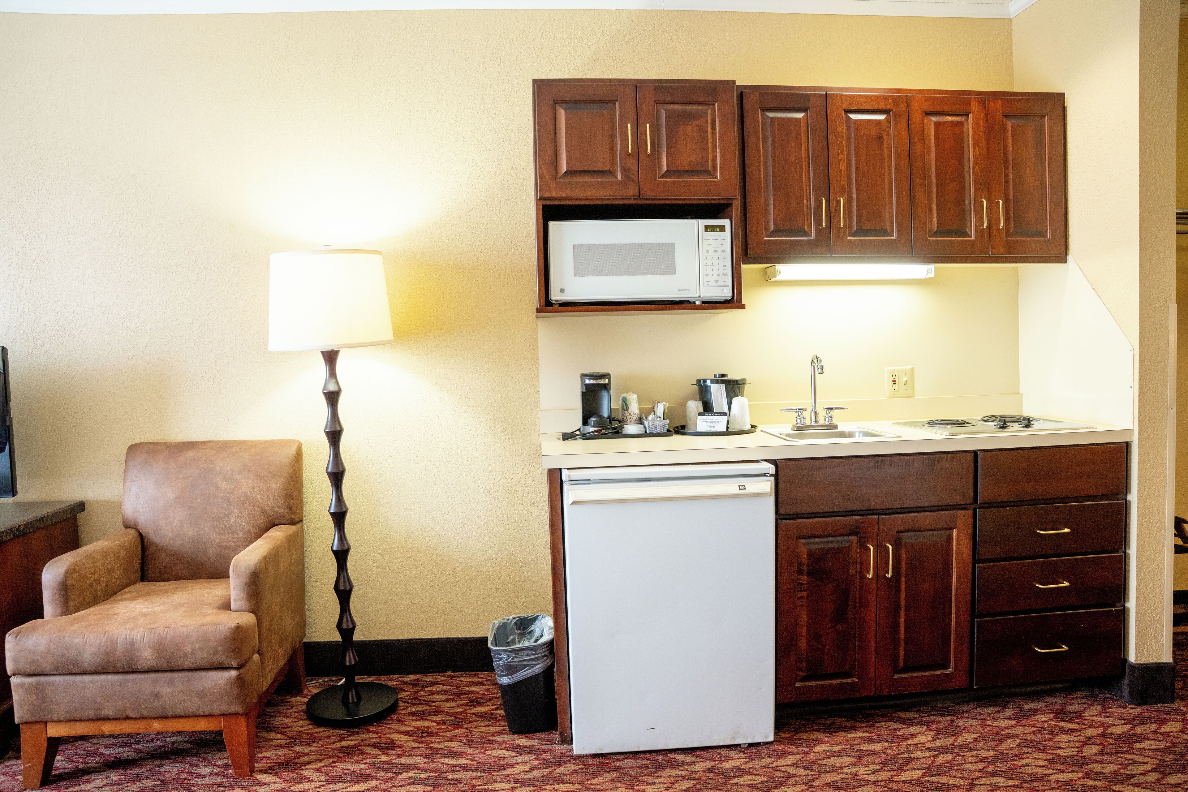 A compact kitchenette with a microwave, a small refrigerator, and wooden cabinets.