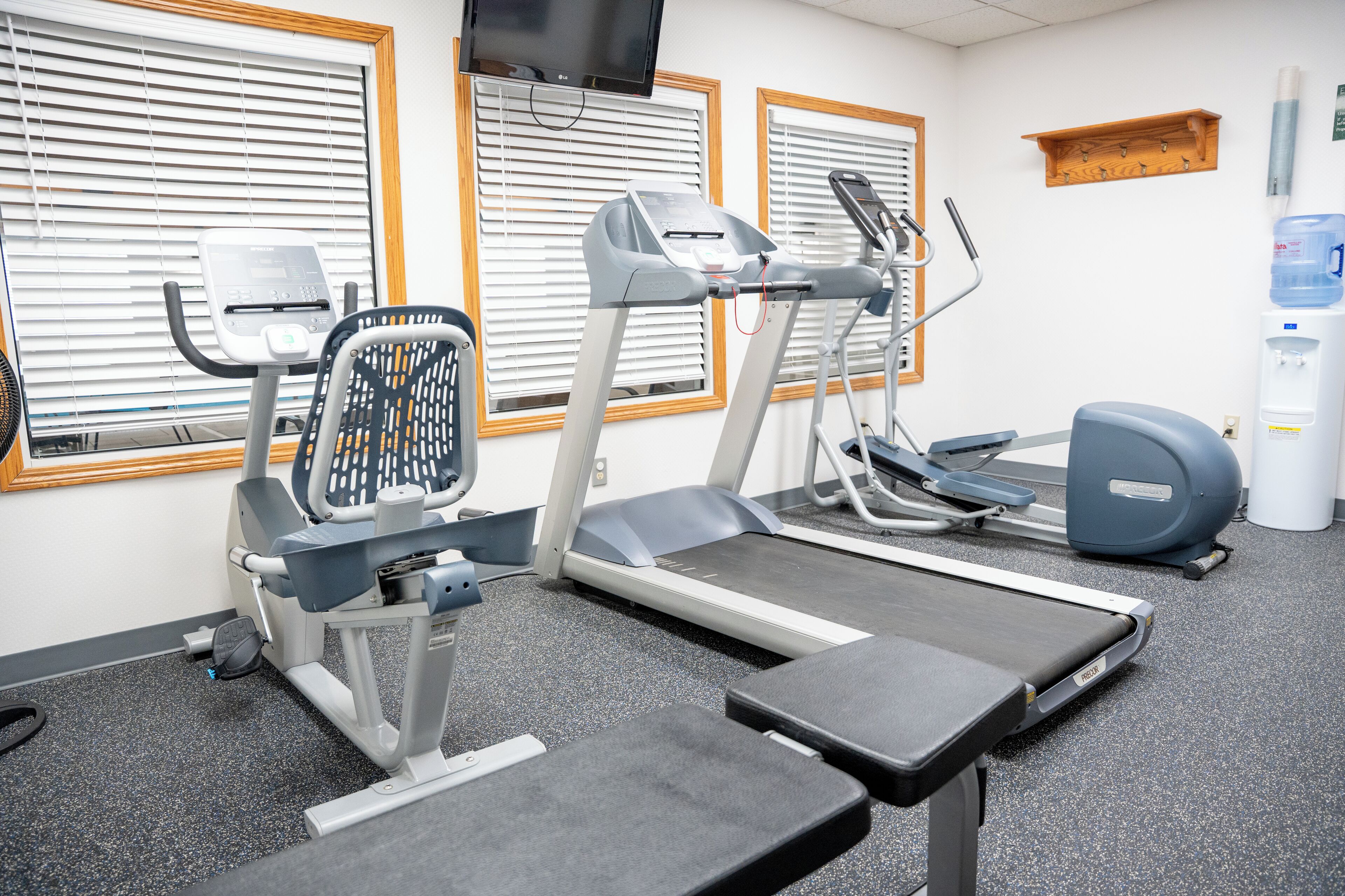 Une salle de sport équipée de tapis de course, d’un appareil elliptique et d’un banc de musculation.