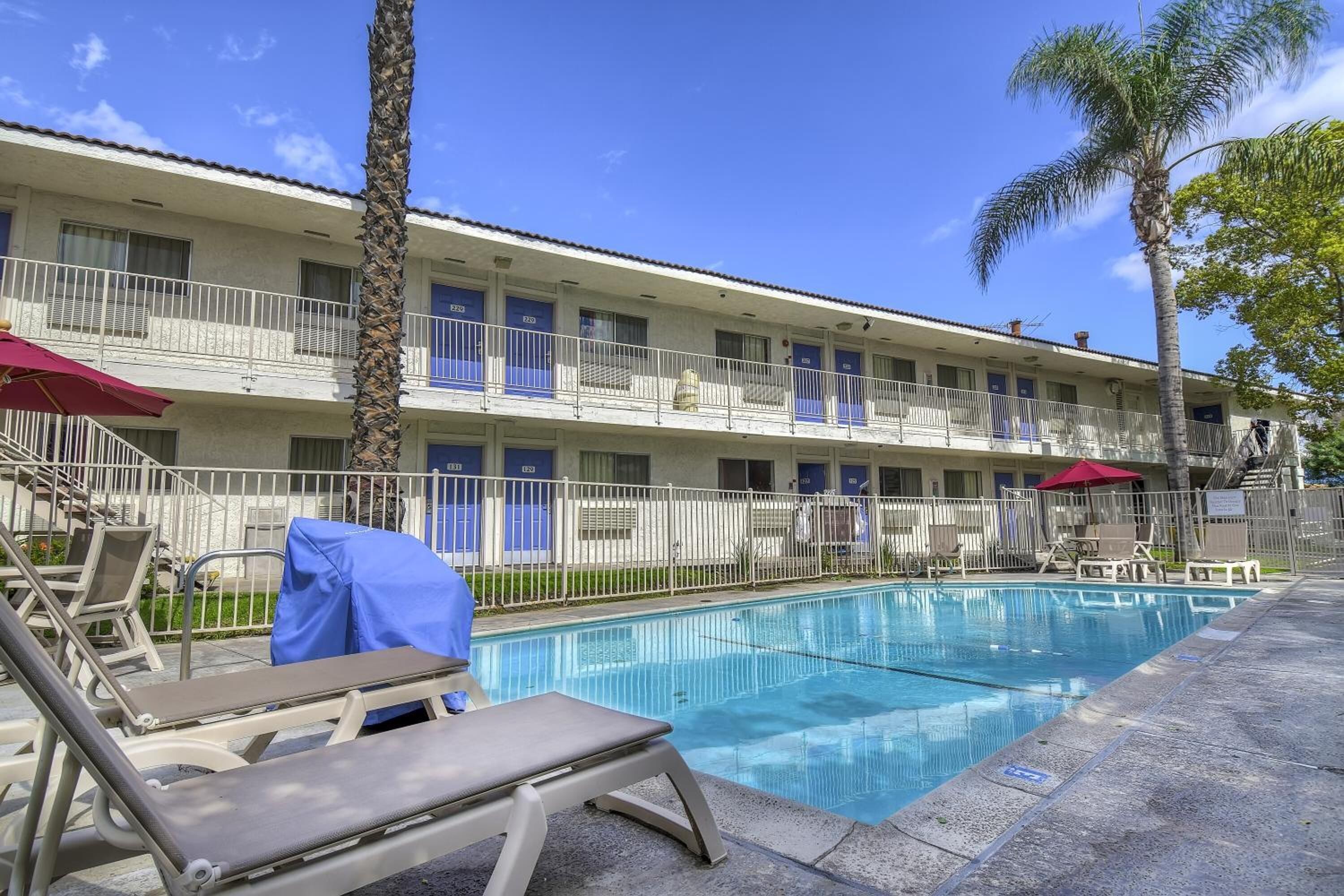 A hotel with a pool area, including lounge chairs and umbrellas.