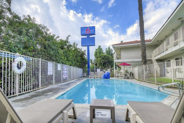 A swimming pool with lounge chairs, a lifebuoy, and a 'No Swimming' sign. - Motel 6 Chino, CA - Los Angeles Ontario (Chino)