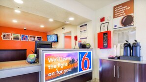 A motel reception desk with a digital screen displaying a message, a telephone, and a coffee machine. - Motel 6 Chino, CA - Los Angeles Ontario (Chino)