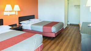 A hotel room with two beds, a desk, and a chair.