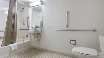 A bathroom with a bathtub, sink, toilet, and grab bars.