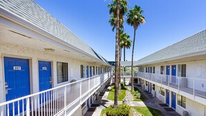 A motel with a central courtyard, featuring palm trees and a small garden. - Motel 6 Mesa, AZ - South (Mesa)