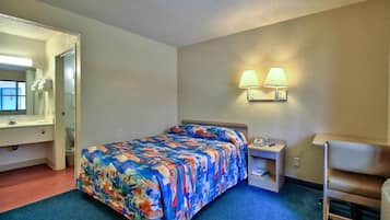 A hotel room with a bed, a nightstand, a desk, a chair, a bathroom with a mirror and sink, and two wall-mounted lamps.