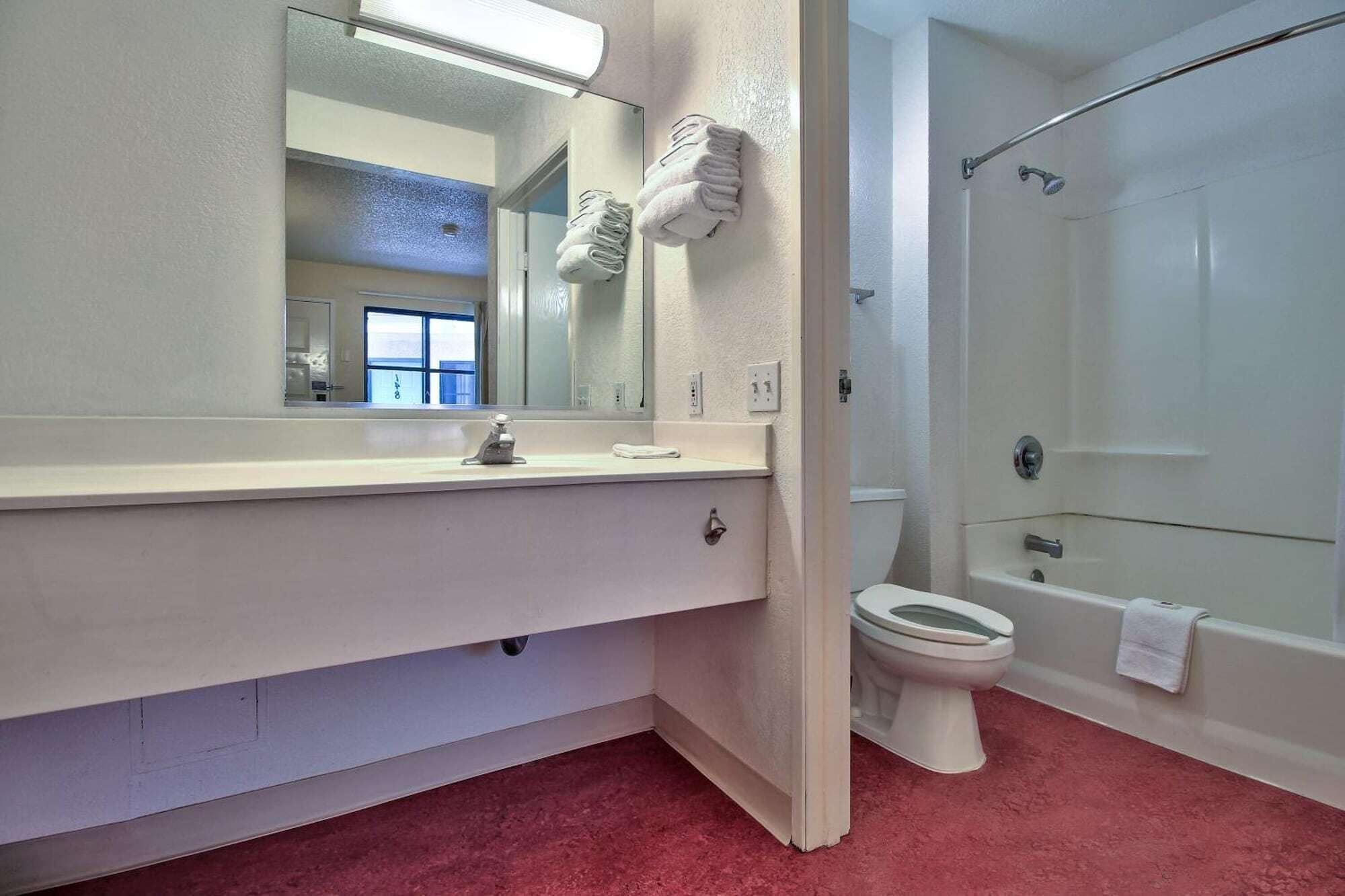 Un baño con lavamanos blanco, espejo, inodoro y ducha.