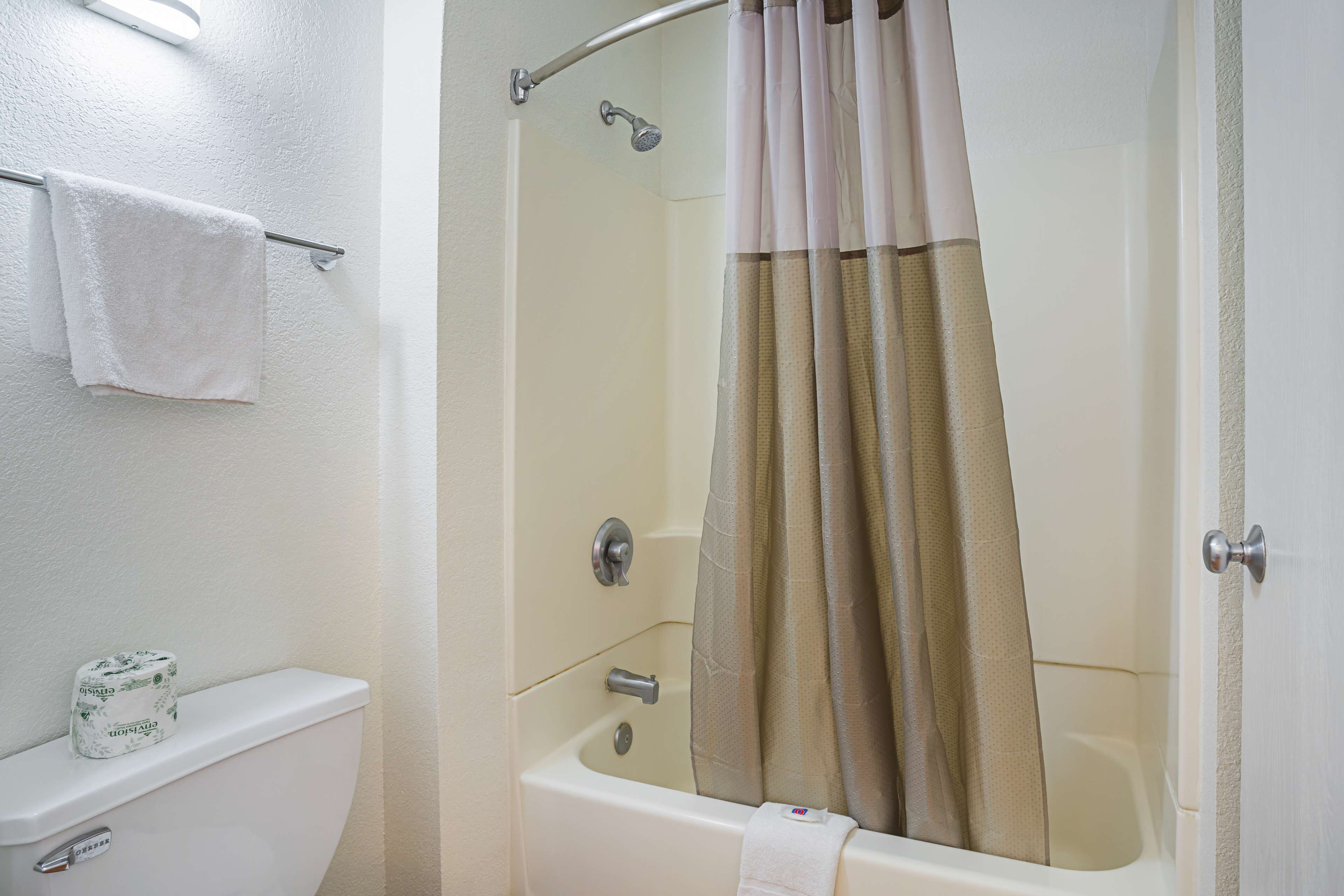 Une salle de bain équipée de toilettes, d’un rideau de douche et d’un porte-serviettes.