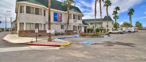 A motel with a '6' sign, parking spaces, and palm trees.
