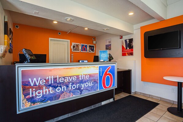 A hotel reception desk with a large sign reading "We'll leave the light on for you." - Motel 6 Yuma, AZ - East (Yuma)