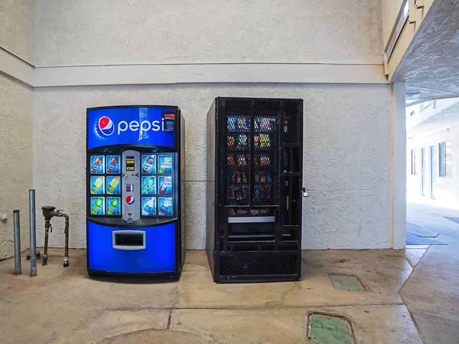 A vending machine with a Pepsi logo and a black vending machine with colorful drink options.