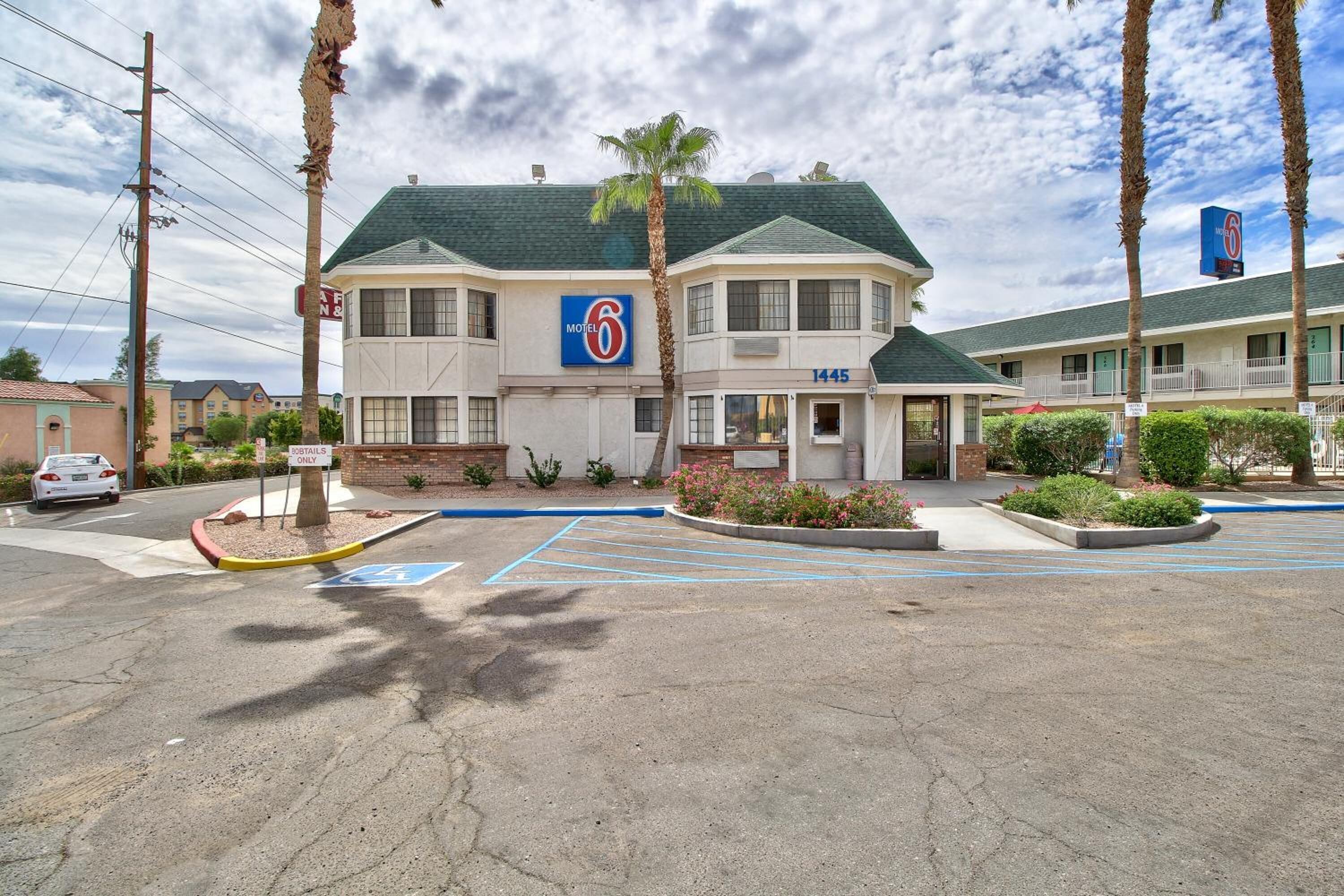 A motel with a green roof, a '6' sign, and a number '1445' on the building.