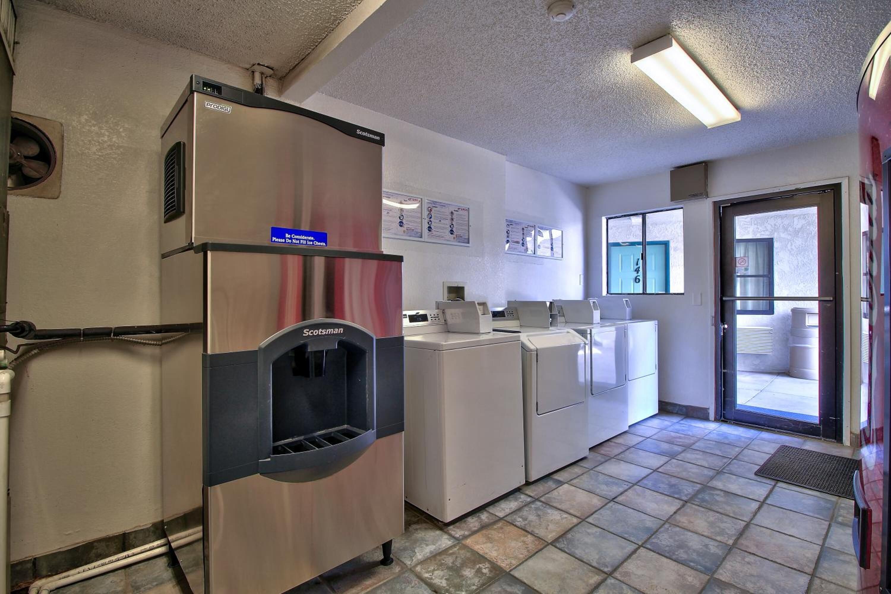 A laundry facility with a water dispenser, washing machines, and dryers.