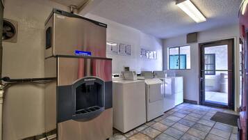 A laundry facility with a water dispenser, washing machines, and dryers.