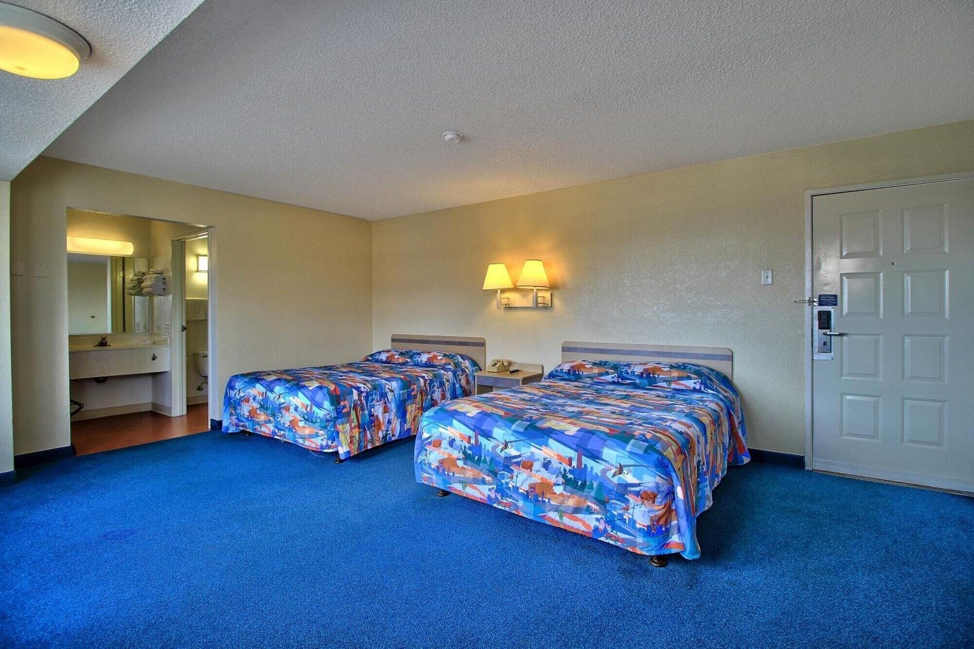 Quarto de hotel com duas camas, banheiro e porta.