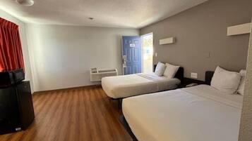Une chambre d’hôtel avec deux lits, une télévision et une porte donnant sur l’extérieur.