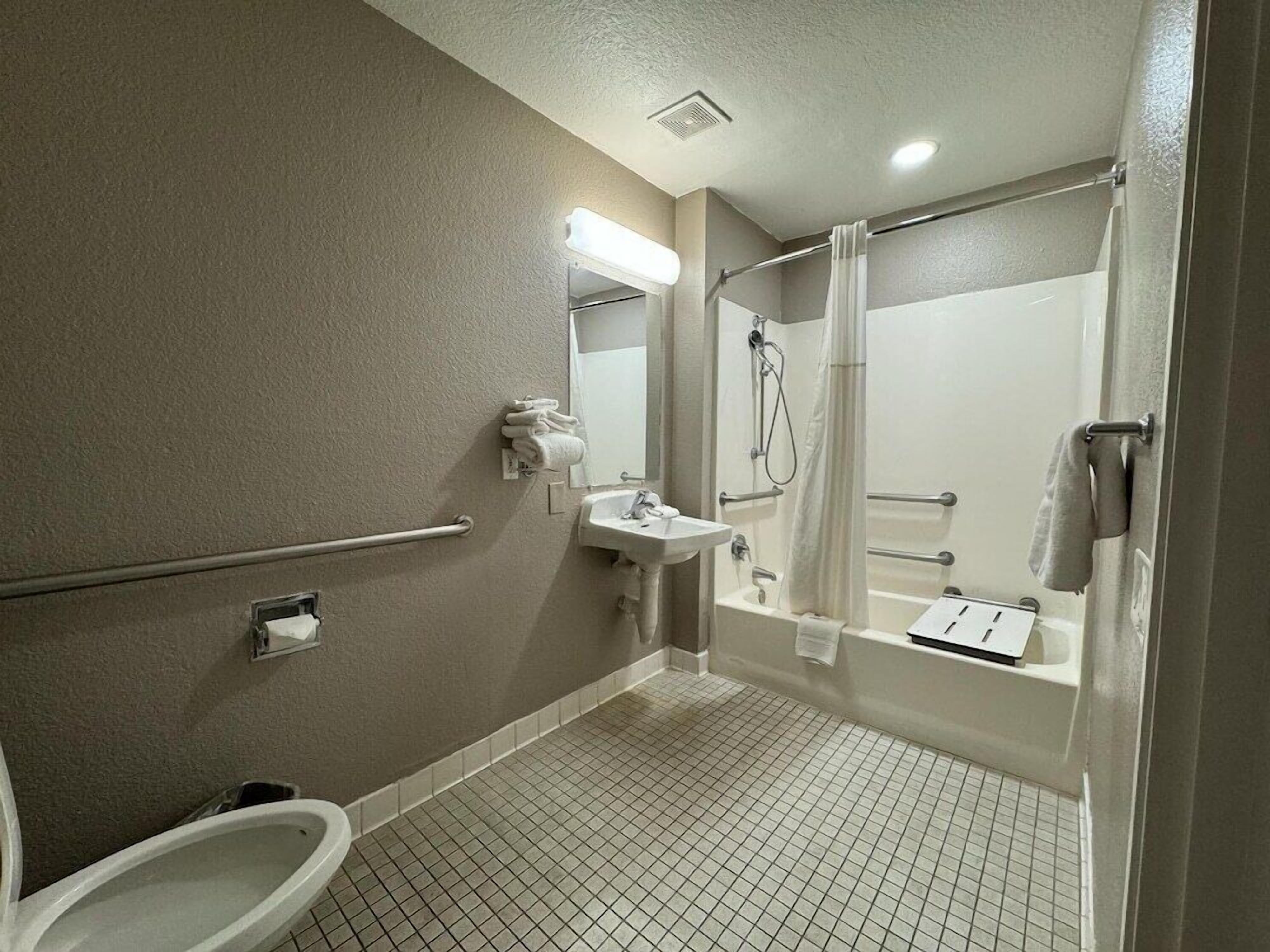 Un baño de hotel estándar con inodoro, lavamanos y zona de ducha.