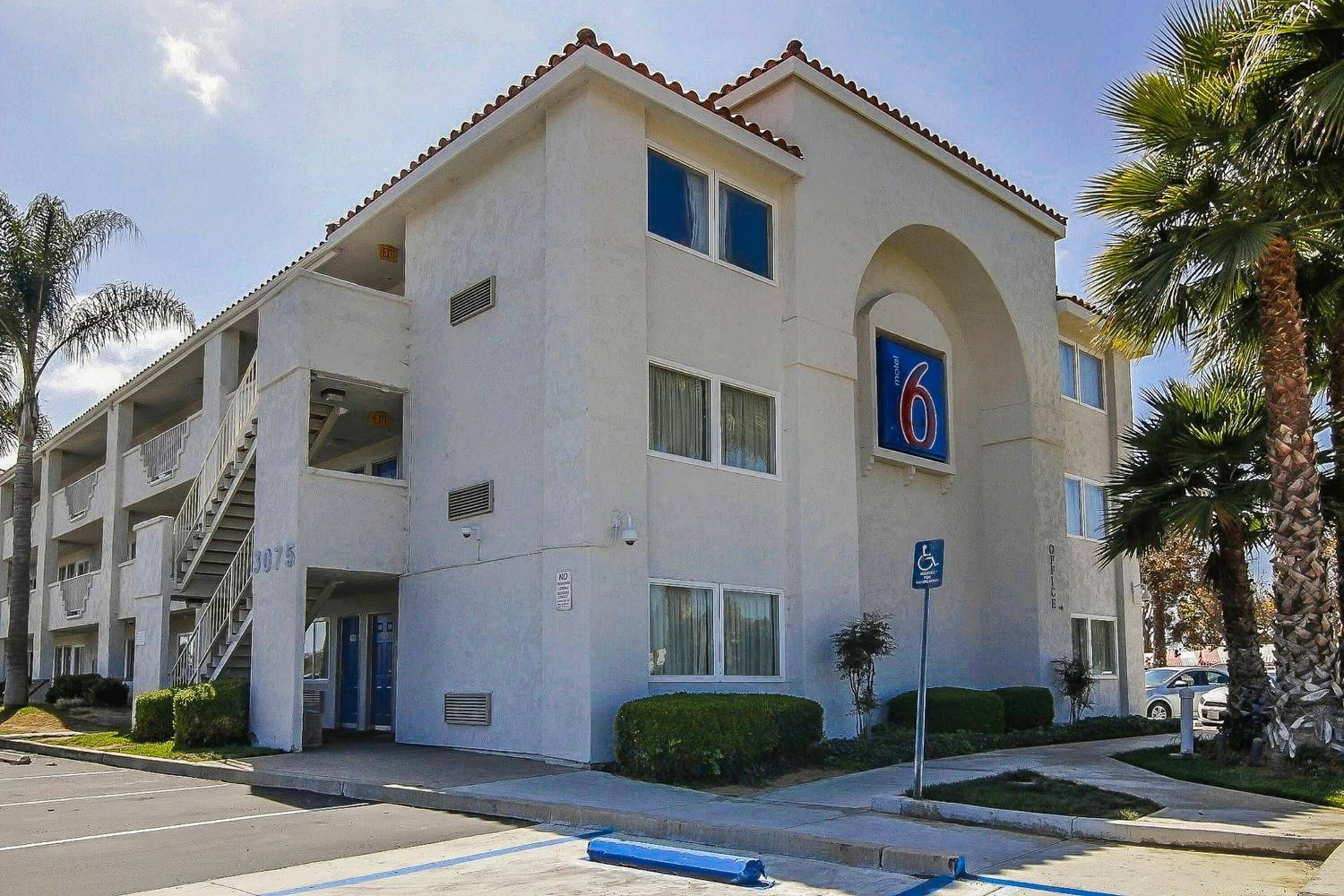 A multi-story building with a beige facade, a blue wheelchair accessibility sign, and a parking garage entrance.