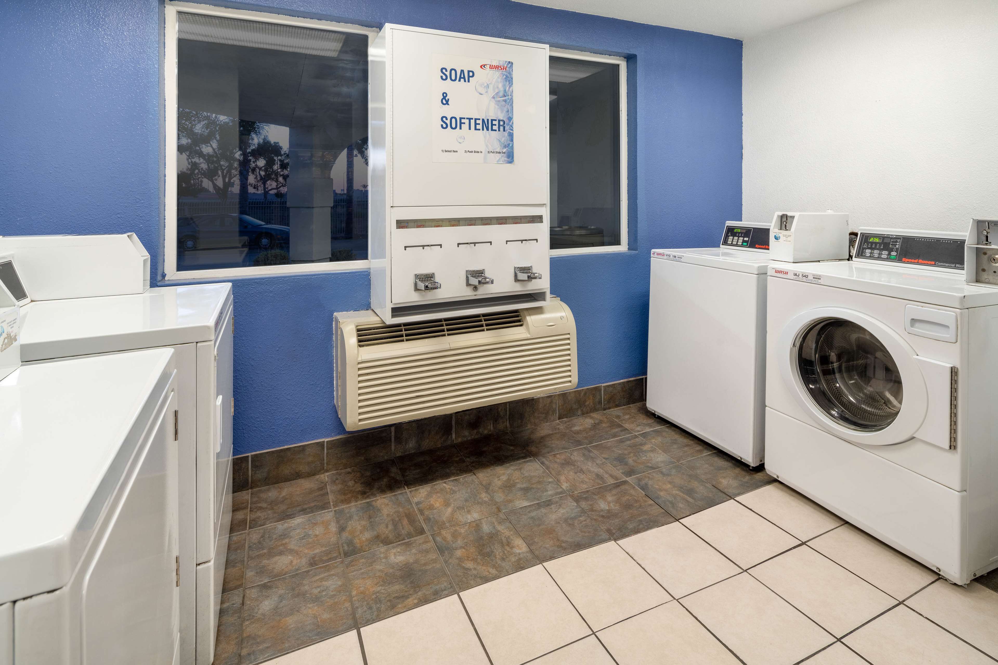 A laundry facility with a soap and softener dispenser, a washing machine, and a dryer.
