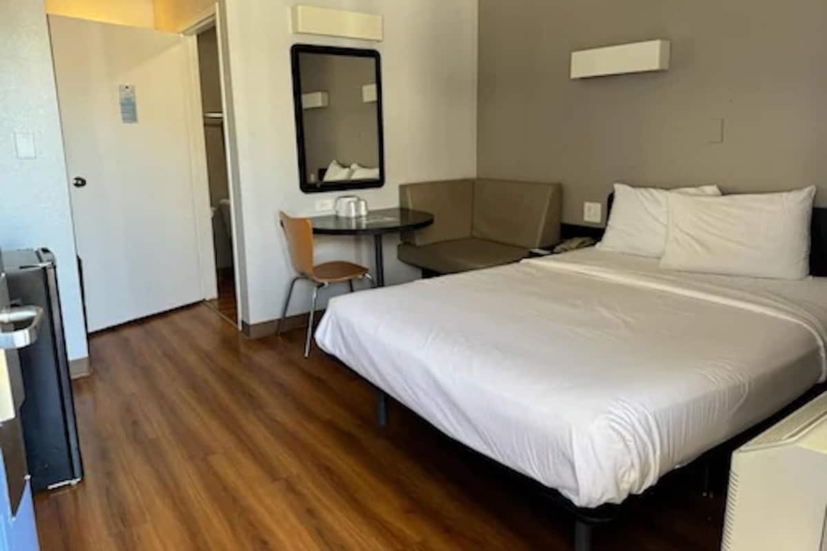 Een hotelkamer met een bed, een bureau, een stoel en een spiegel.