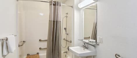 A modern bathroom with a glass-enclosed shower, a white sink, and a mirror.
