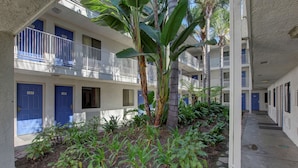A multi-story building with blue doors numbered 127, 129, and 229. - Motel 6 Bellflower, CA - Los Angeles (Bellflower)