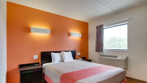 Habitación de hotel con una cama grande, dos mesitas de noche, una ventana con cortinas e un equipo de aire acondicionado.