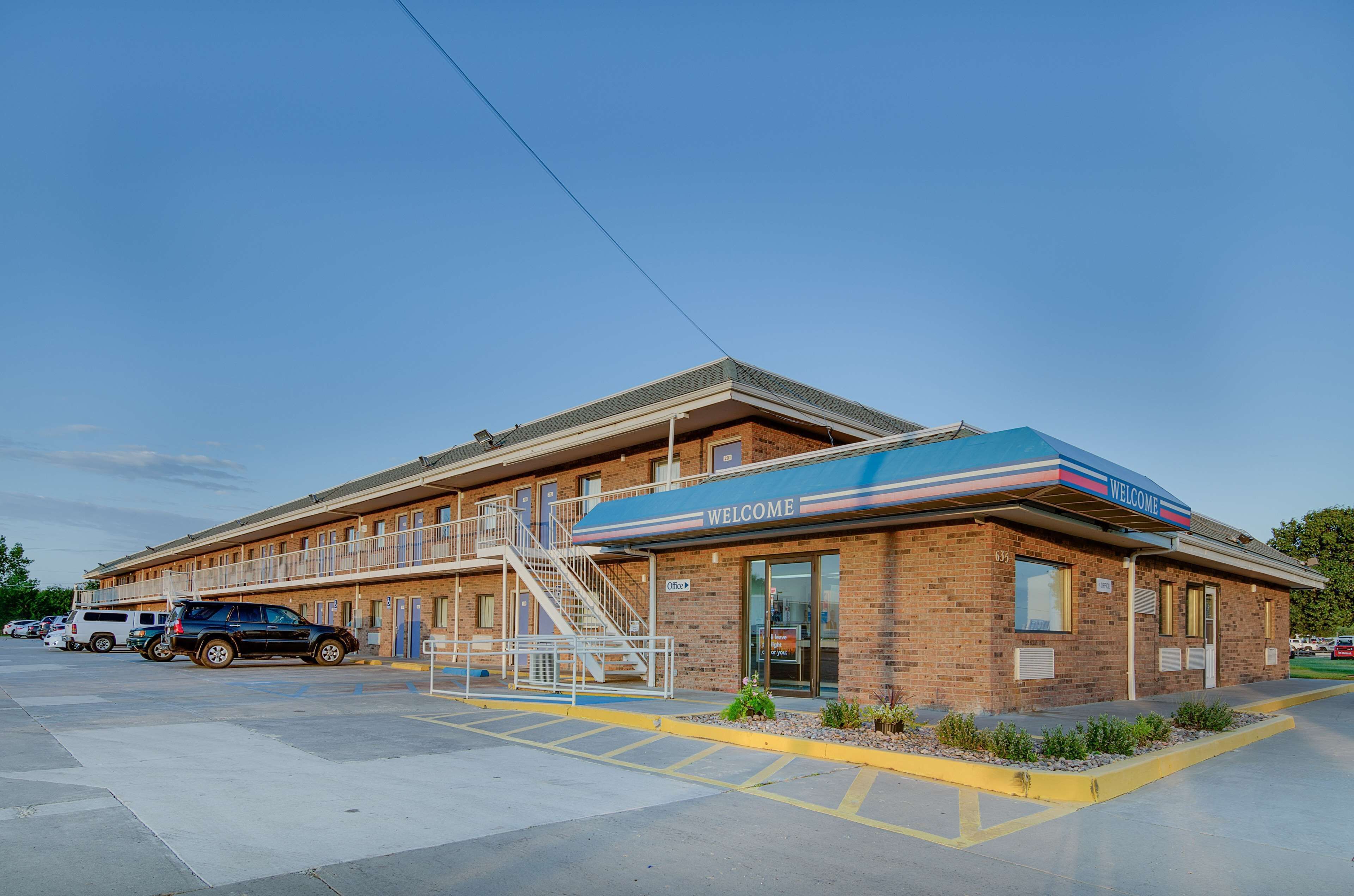 A motel with a 'WELCOME' sign, a covered parking area, and a brick building facade.