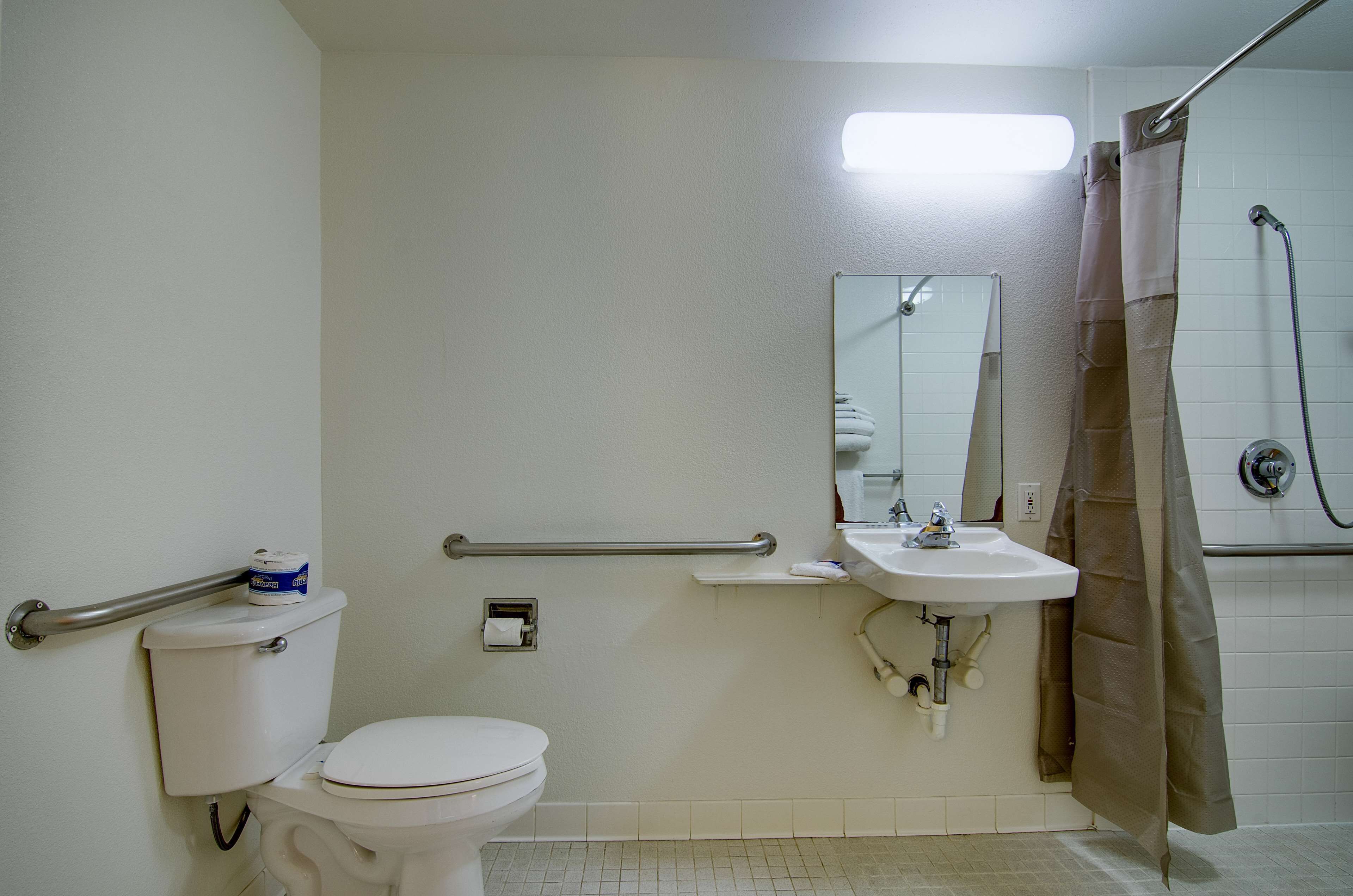 A bathroom with a toilet, sink, mirror, and shower.