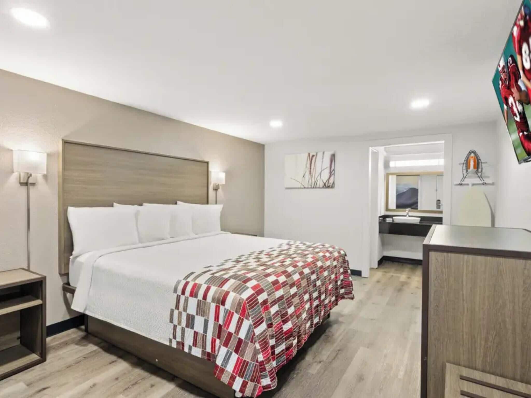 Une chambre d’hôtel comprenant un lit, des tables de chevet, un bureau et un miroir.